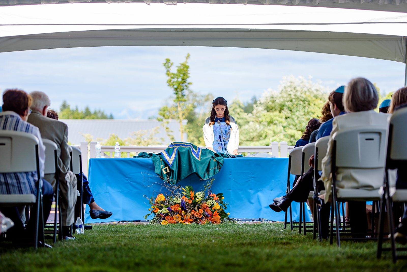 A girl reads from the torah at an outdoor bat mitzvah under a large tent at a Chabad in Seattle