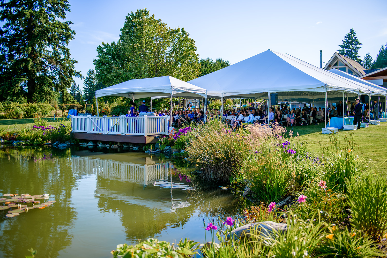 An outdoor mitzvah taking place under a large tent next to a garden pond at a Chabad in Seattle