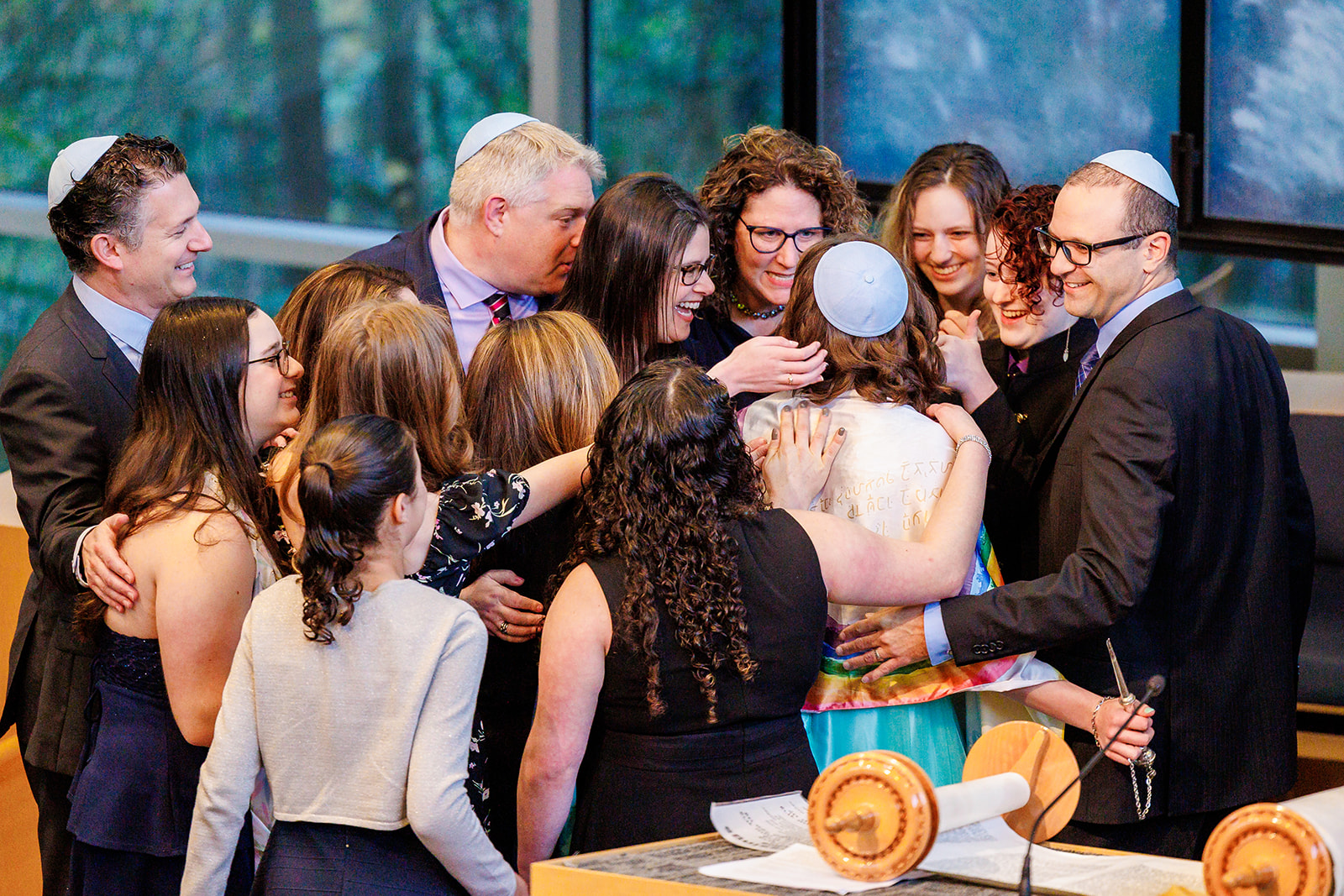 A teenage girl is hugged and celebrated after reading from the torah during her Bat Mitzvah surrounded by family after attending Hebrew Schools In Seattle