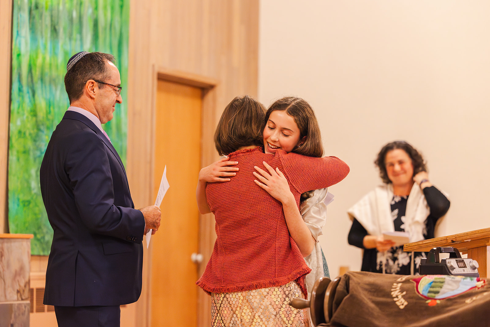 A teenage girl hugs mom after completing her reading during her Bat Mitzvah