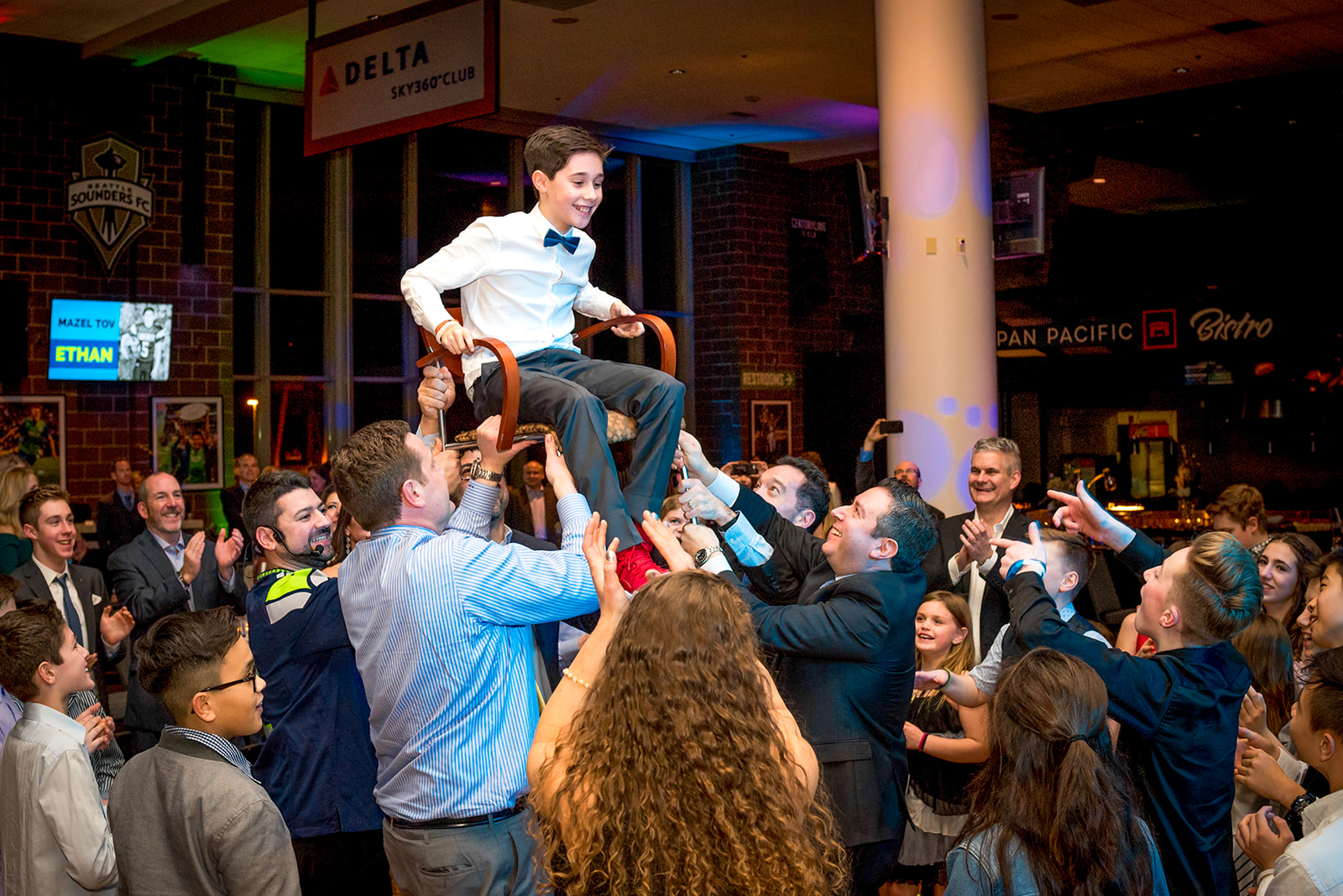 A teen boy is lifted on the dance floor during his Mitzvah in a restaurant after attending Jewish Day School of Metropolitan Seattle