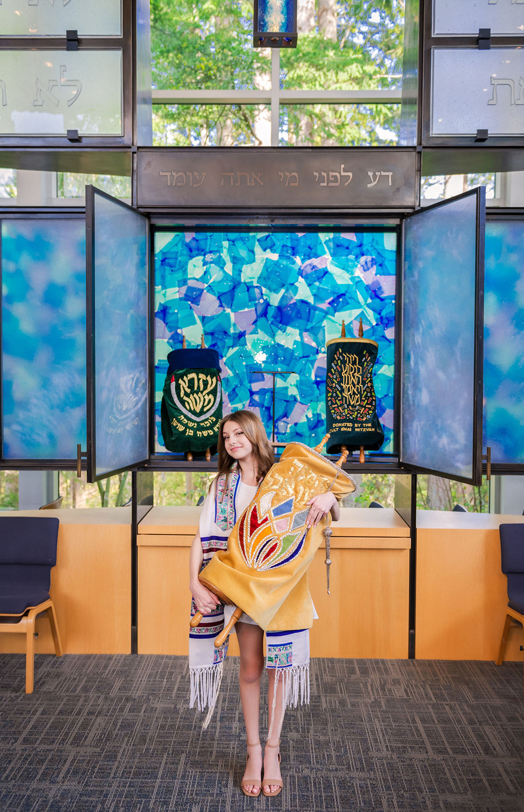 A teenage girl stands in a temple holding the scrolls