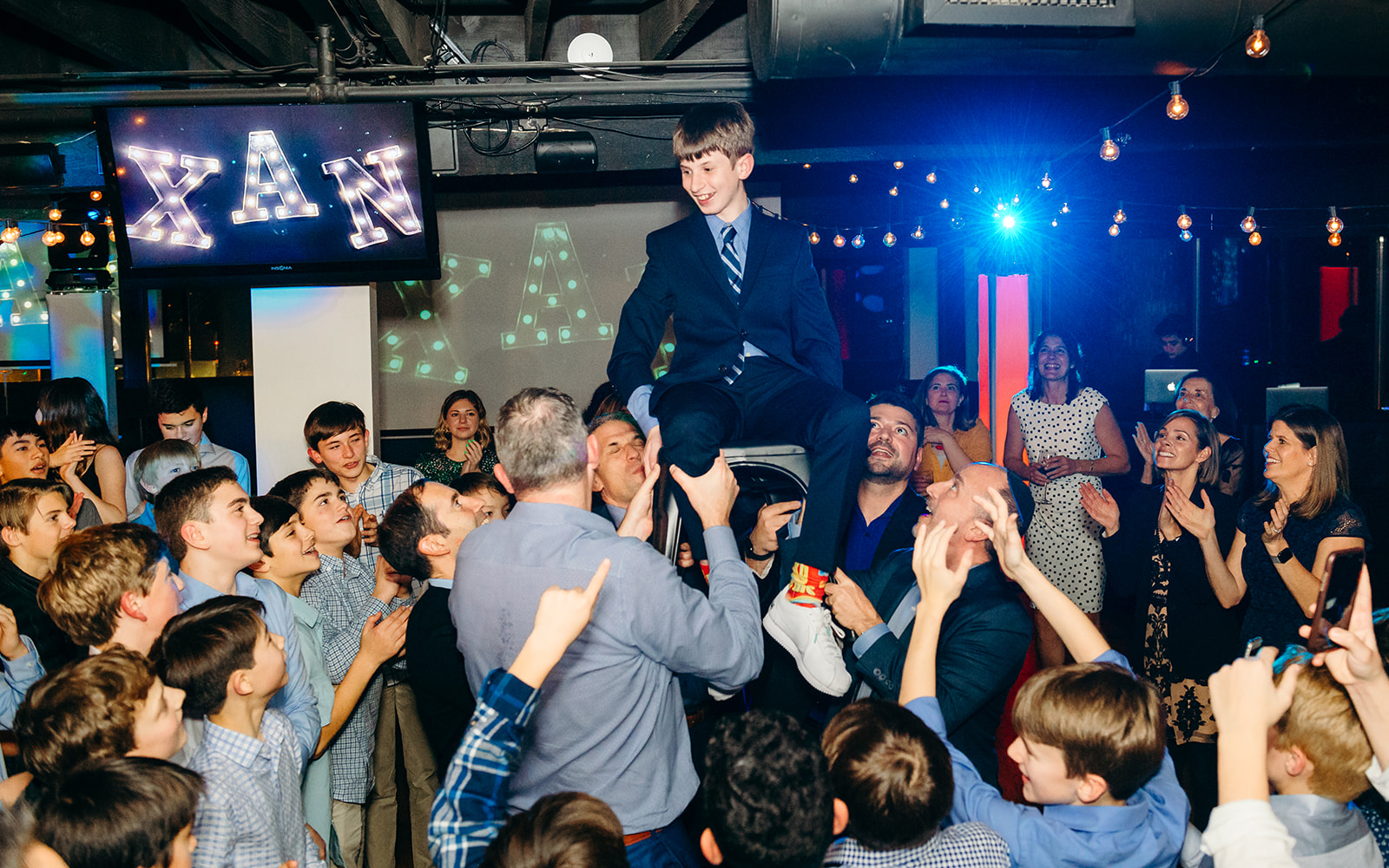 A teen boy is lifted on the dance floor during his Mitzvah before singing with Seattle Jewish Chorale