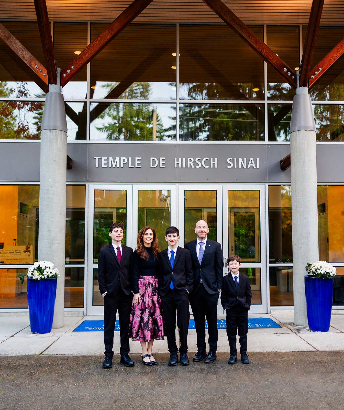 A mother and father stand with their three sons at the front entrance to Temple de Hirsch Sinai after their middle of three sons Mitzvah