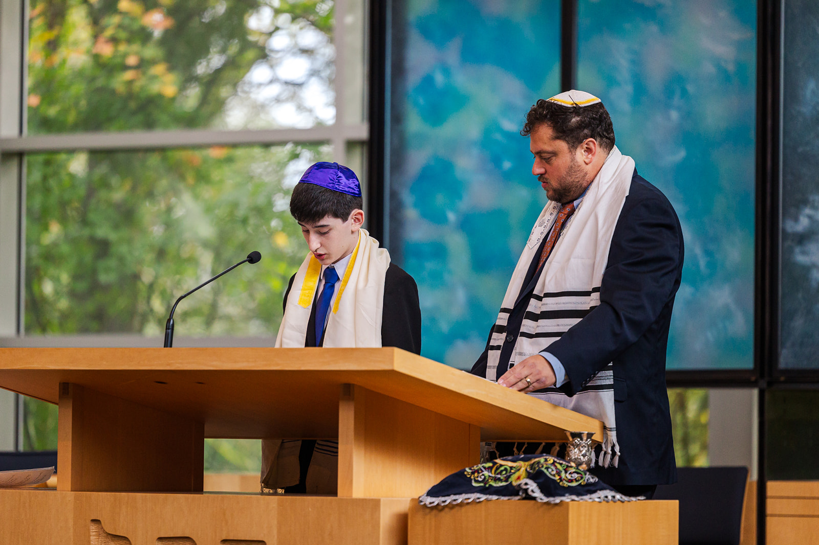 A boy reads from the Torah with his Rabbi during his bat mitzvah