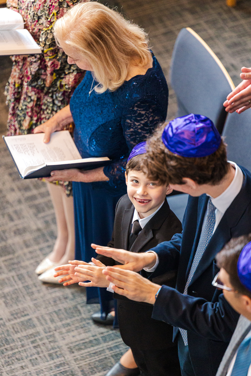 A young boy smiles up to his older brother as they clap during a Mitvah at Temple de Hirsch Sinai