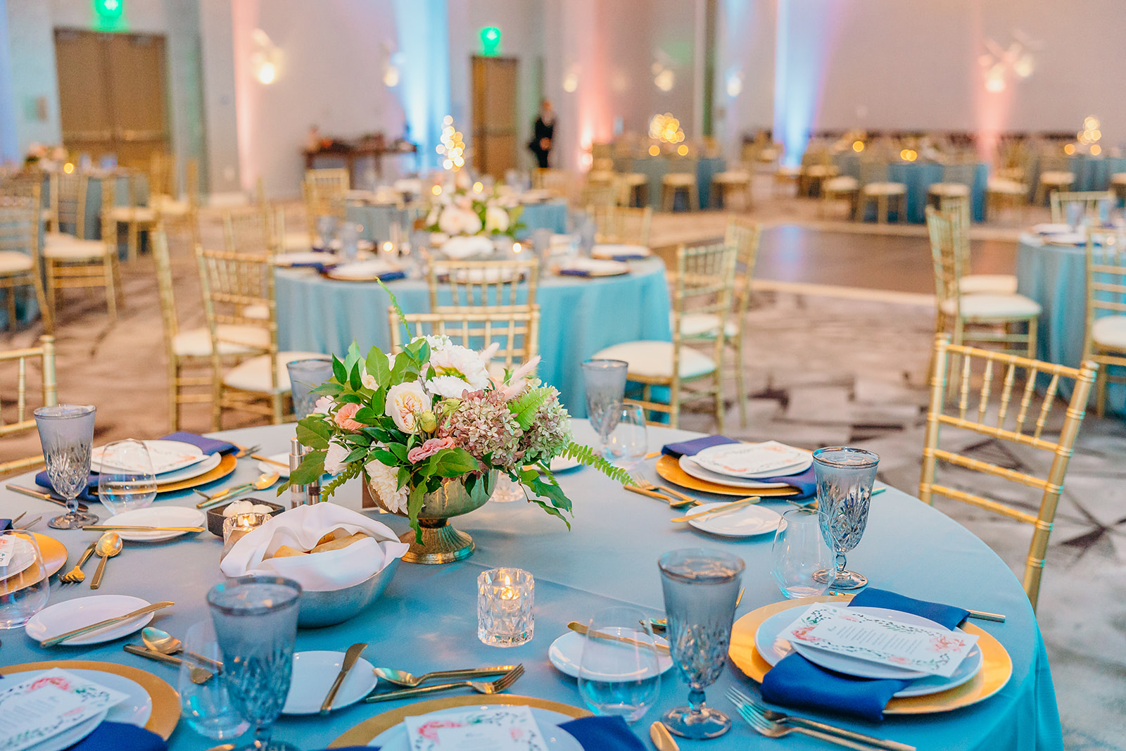 Details of a reception ballroom set up with blue linens and floral centerpieces