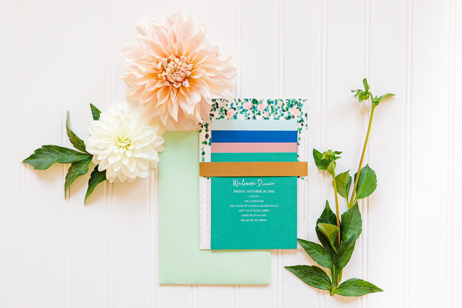 Details of a dinner invitation on a white table with pink and white flowers from Florists in Bellevue