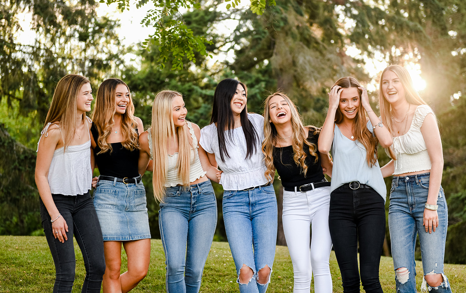 A group of high school seniors laugh together while standing in a park field at sunset after finding high school senior volunteer opportunities seattle