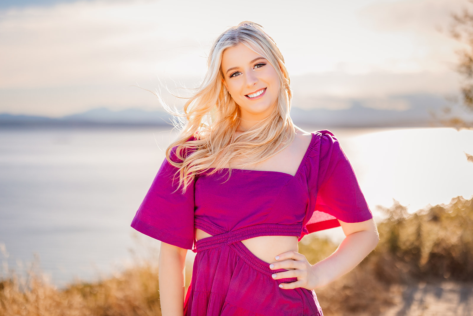 A high school senior in a purple dress stands on a trail overlooking a river after using Makeup Artists Bellevue