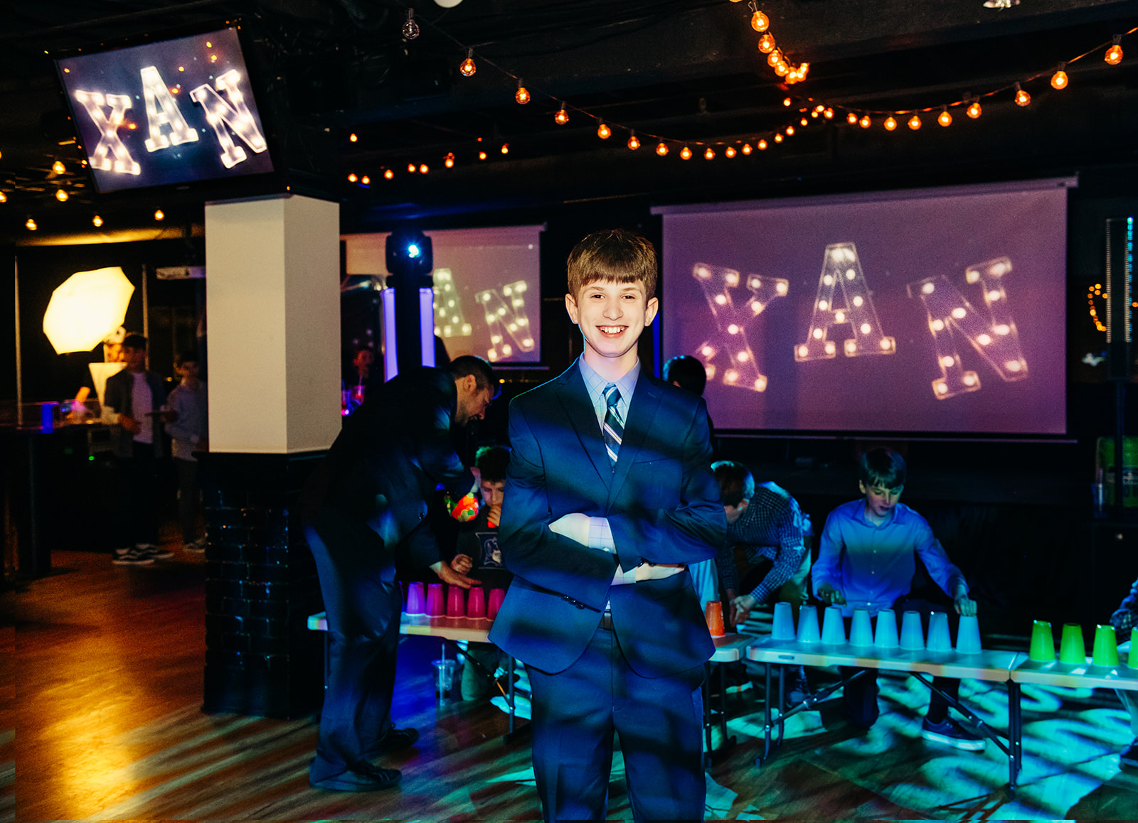 A boy in a blue suit stands in his Mitzvah dance floor while listening to Mitzvah DJs Seattle