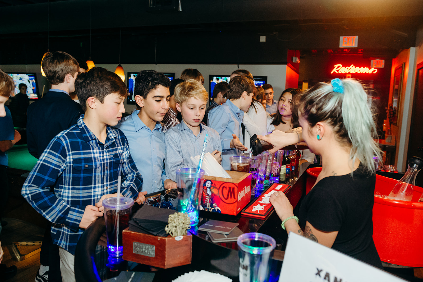 A group of boys in nicer clothes order drinks from a bartender at a party planned by a Mitzvah planners in Seattle