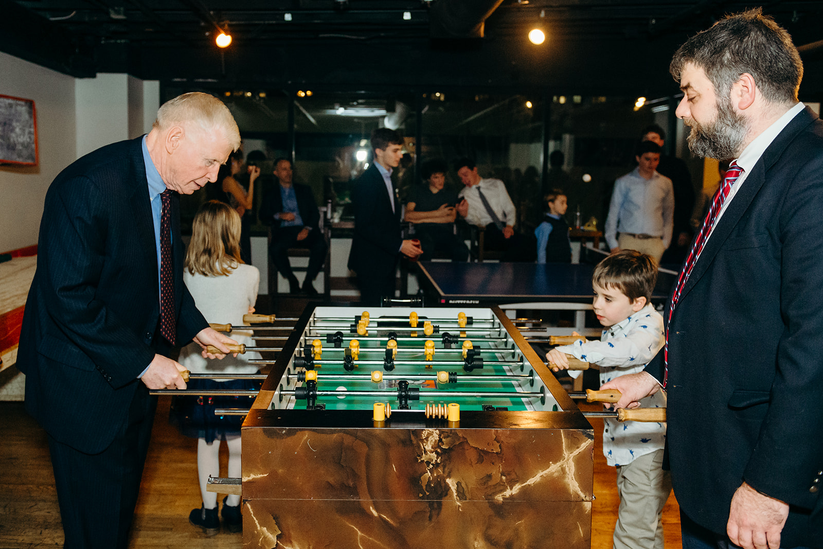 A grandfather plays foosball with a young boy at a Mitzvah thanks to Mitzvah planners in Seattle