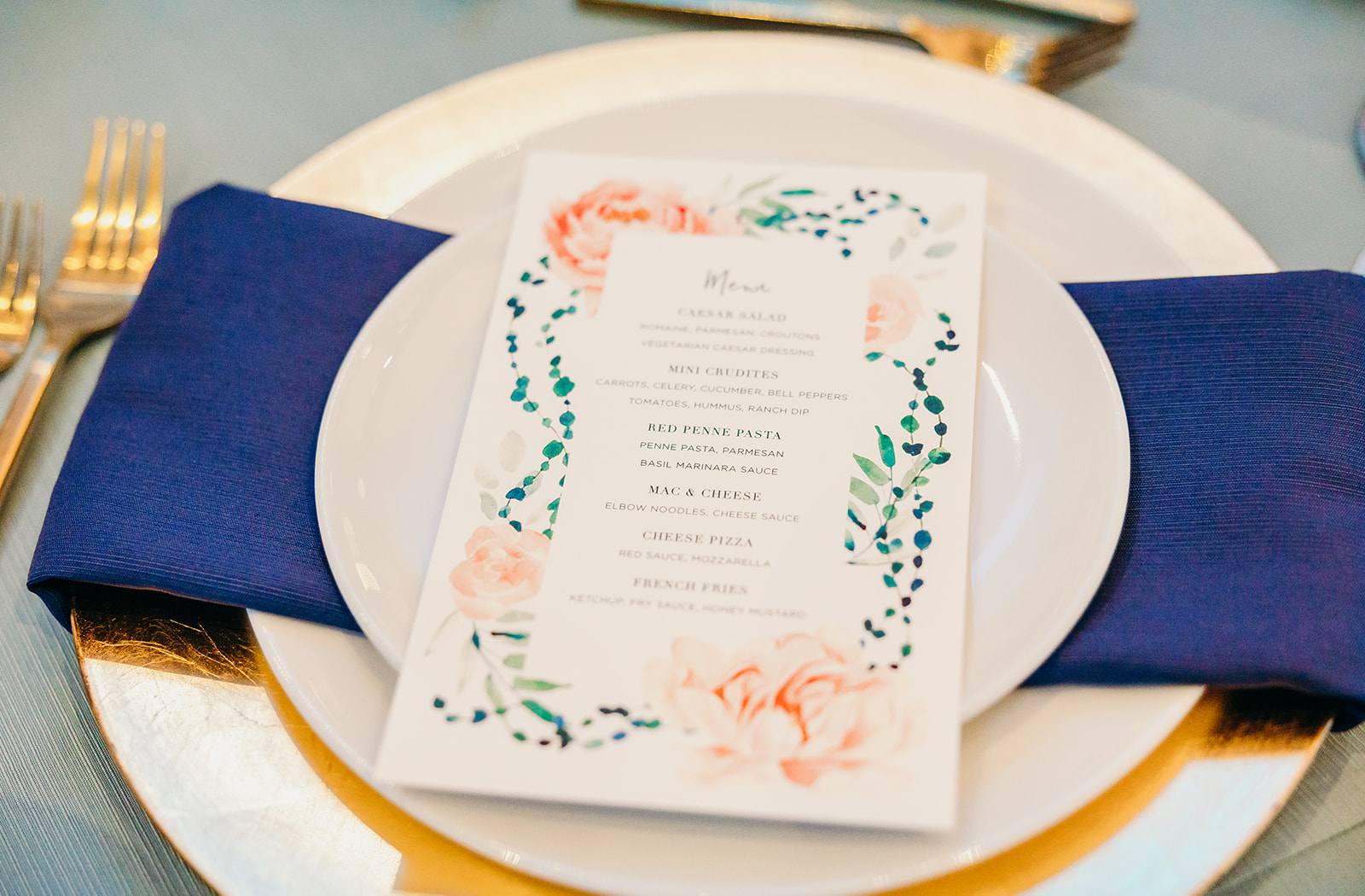 Details of a plate setting with gold silverware and blue napkin