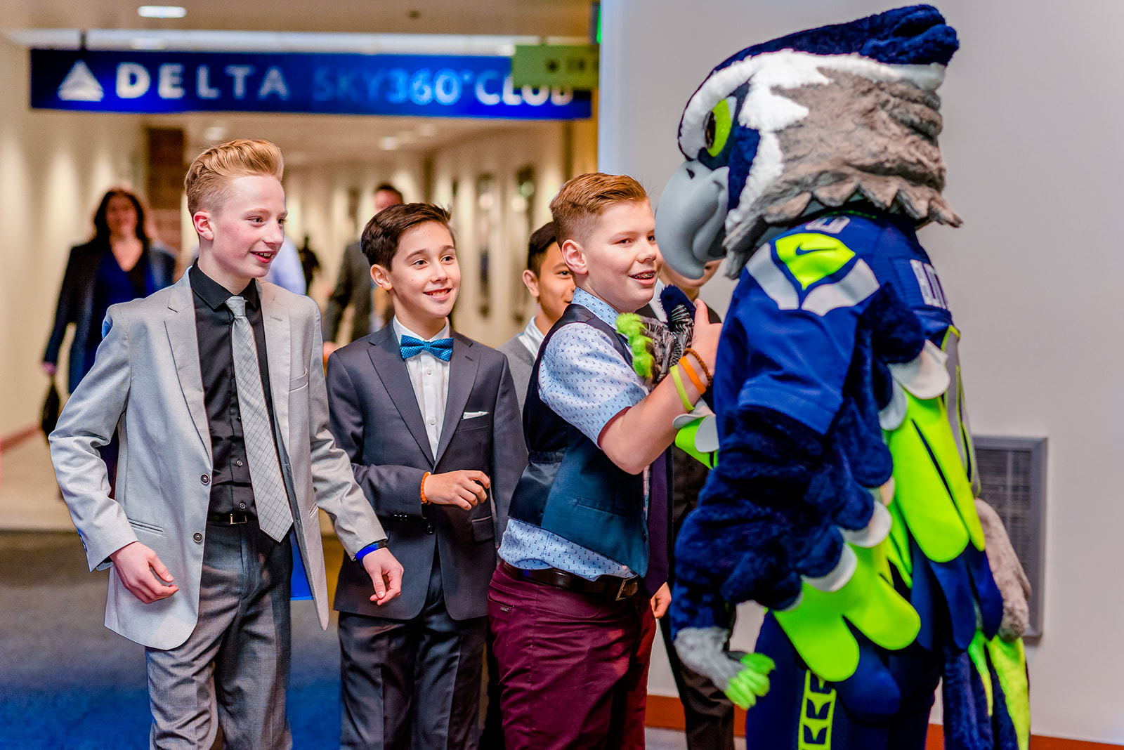 A group of boys meet a football mascot in a hallway wearing suits before visiting the Seattle Jewish Film Festival