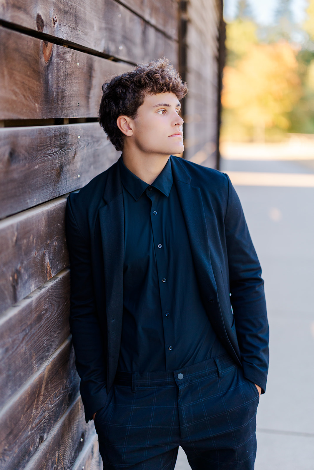 A high school senior leans on a rustic wooden wall with hands in his pockets after visiting Mercer Island Synagogue