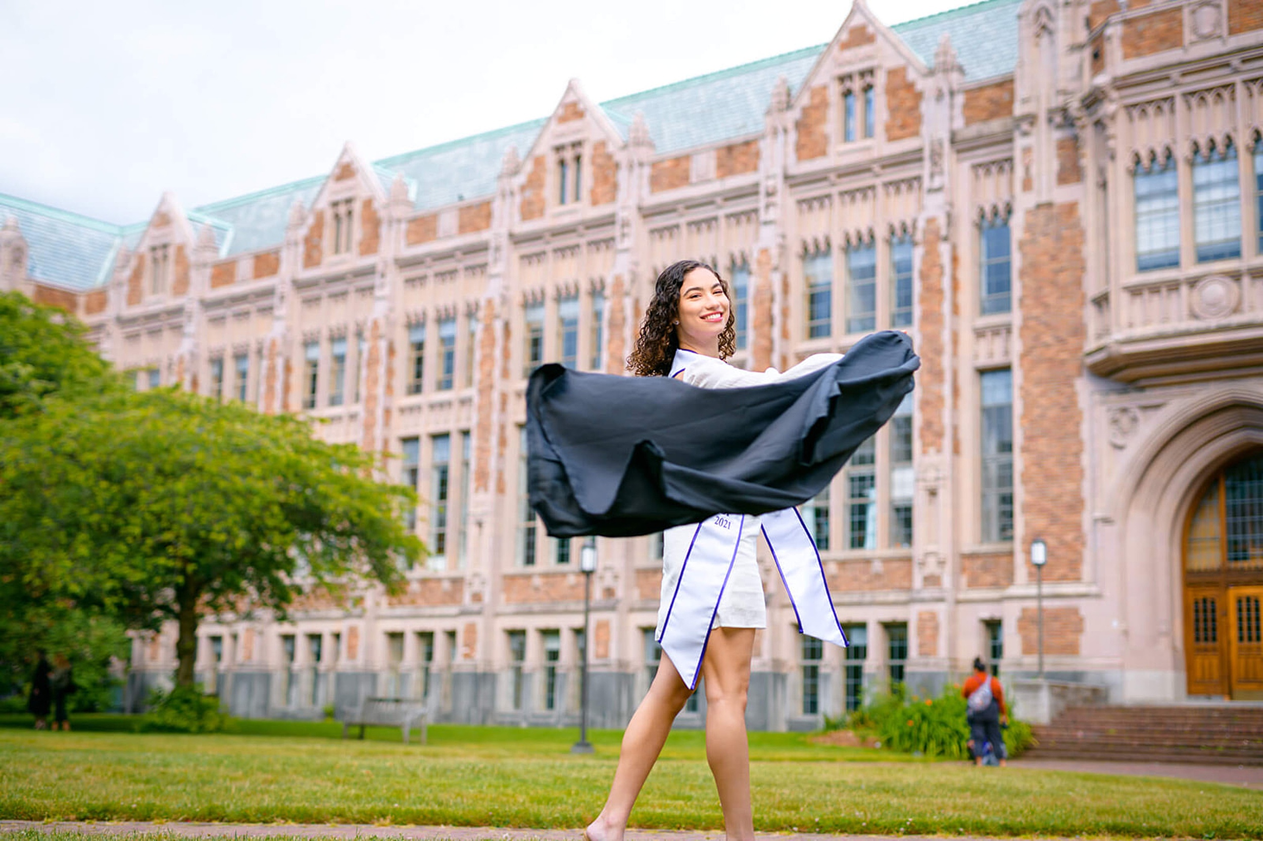 A graduate walks on the campus ground with her gown blwoing in the wind in her hand thanks to Tutoring Mercer Island