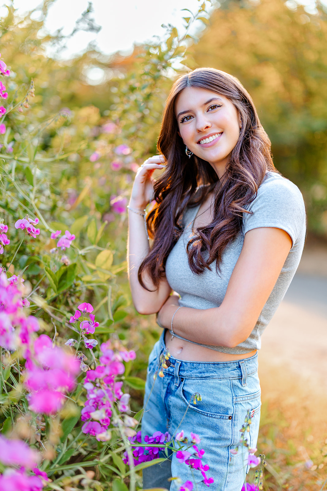 A high school senior stands in a garden at sunset in jeans after attending Bellevue Private Schools