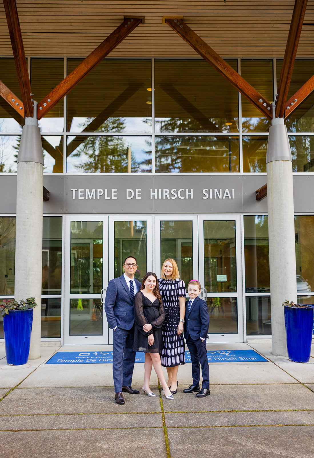 Proud mom and dad stand outside their temple with their teen daughter and younger son