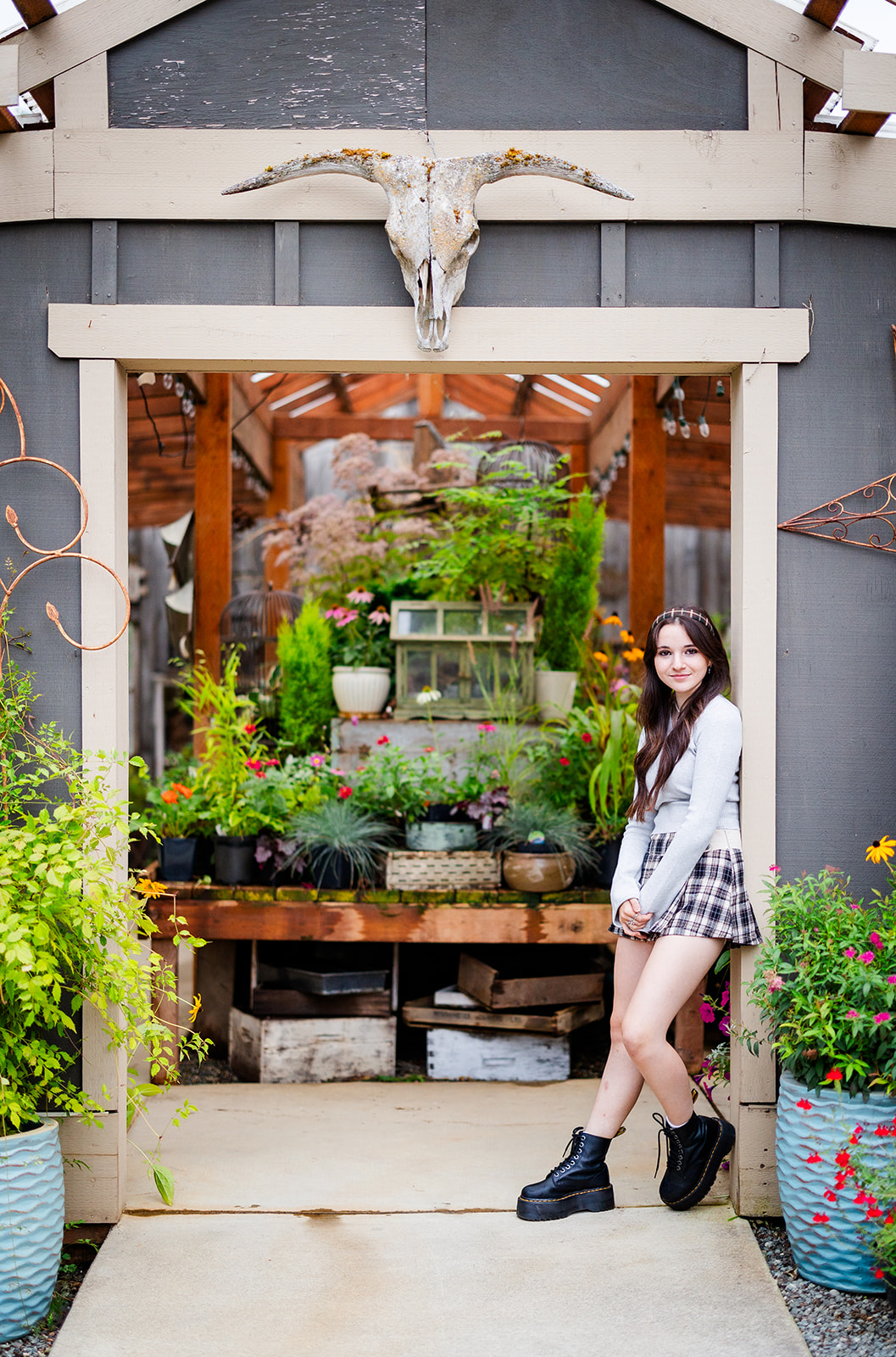 A teenage girl in a skirt and grey top leans in the entrance of a greenhouse before visiting Florists Kirkland, WA