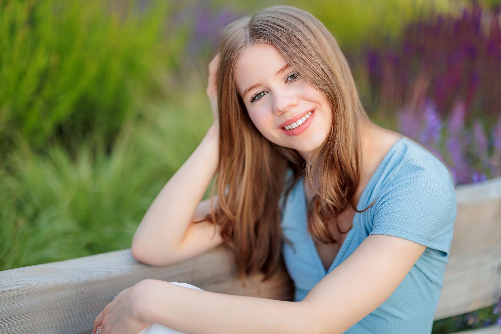 A high school senior sits on a garden bench at sunset while smiling after visiting Issaquah Nail Salons