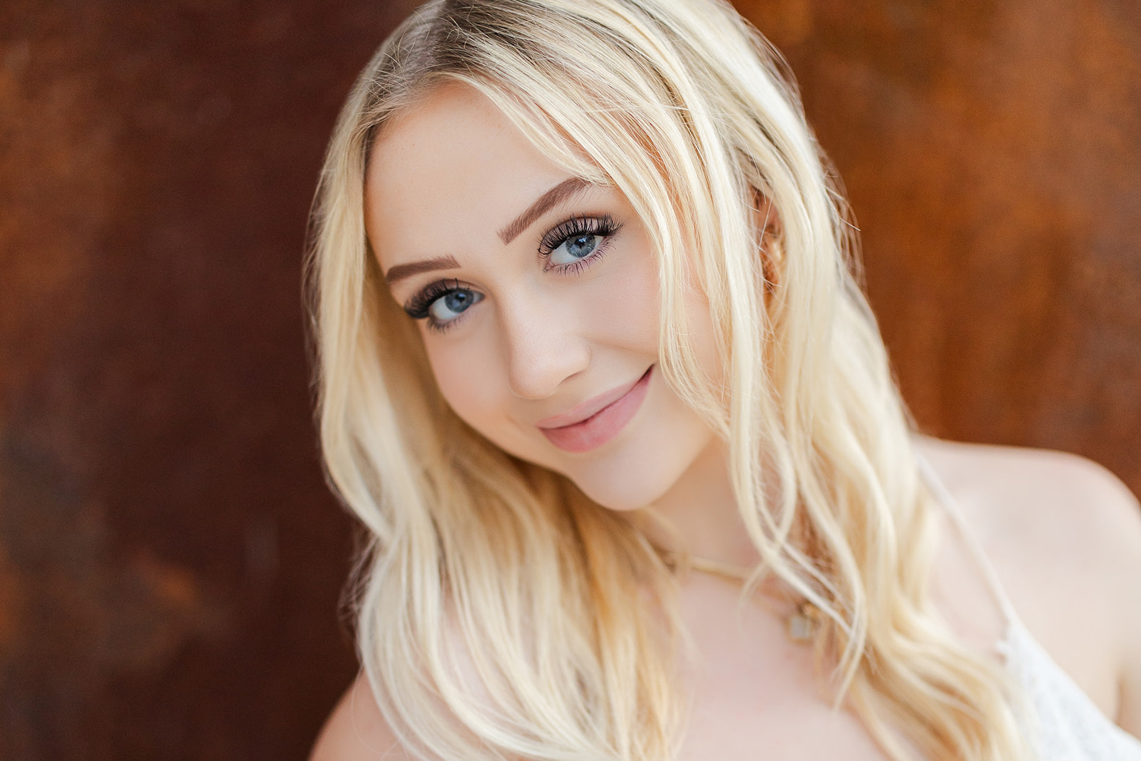 A blonde high school senior smiles for her close up picture after visiting Kirkland Hair Salons