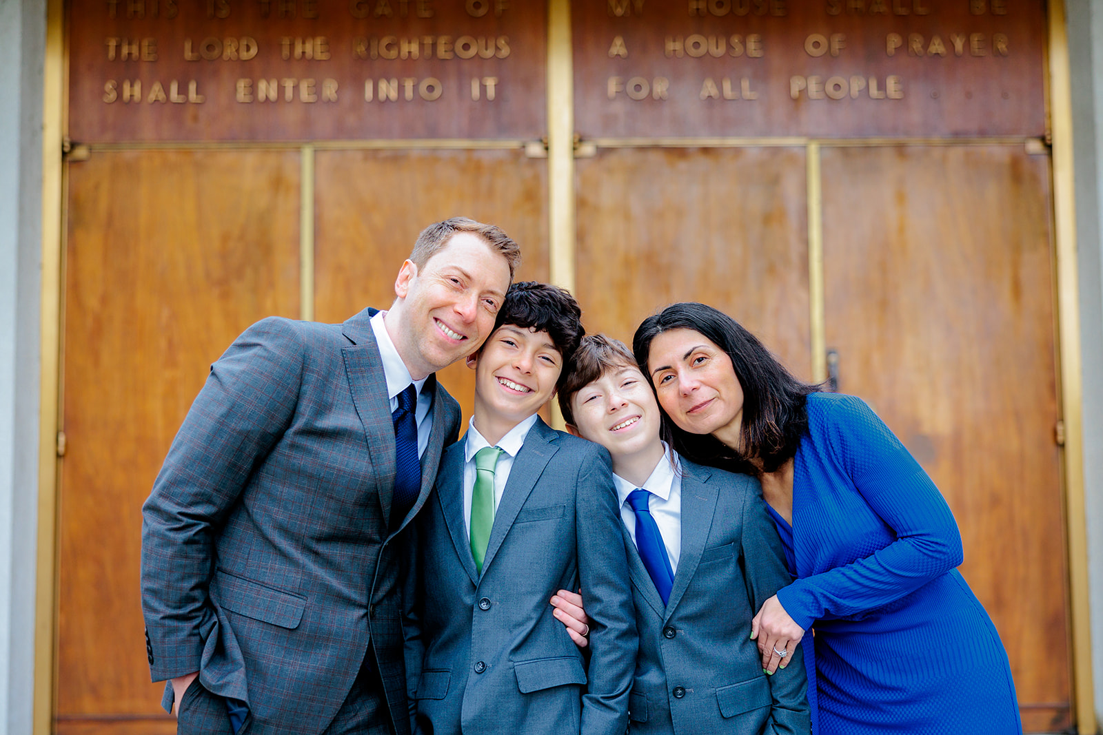 Happy parents smile with their teen sons in suits in front of Chabad of Bellevue