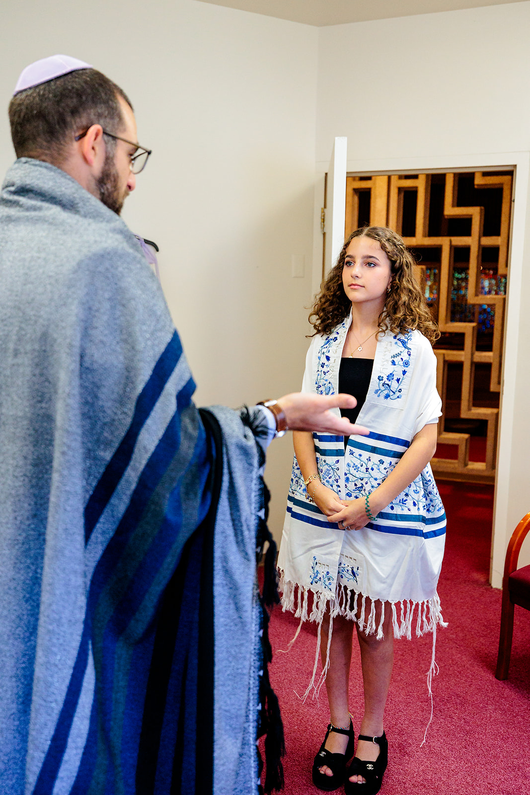 A young girl in her traditional outfit stands while listening to her rabbi at Chabad of Central Cascades