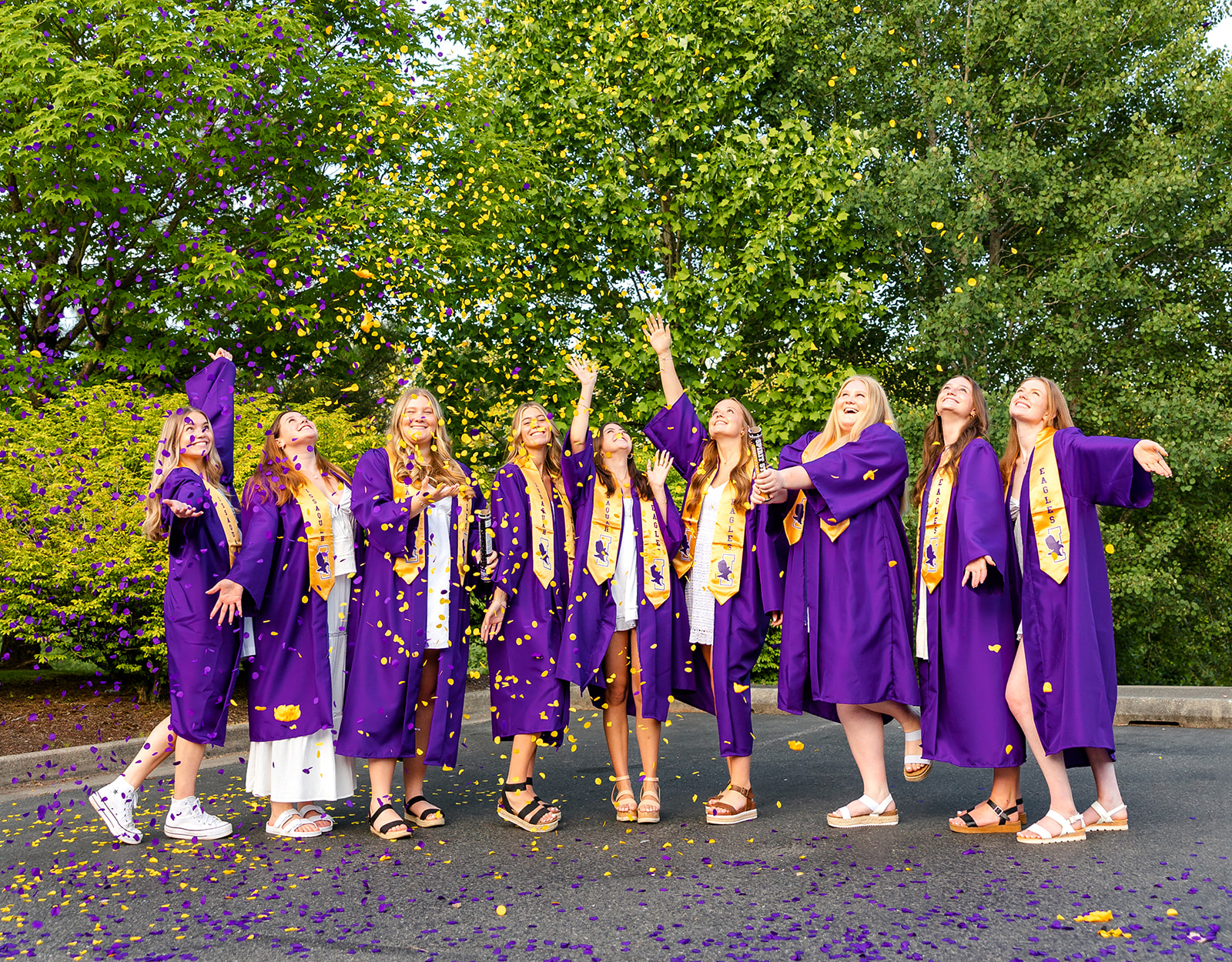 A group of Issaquah High School graduates pop confetti while celebrating in their purple robes