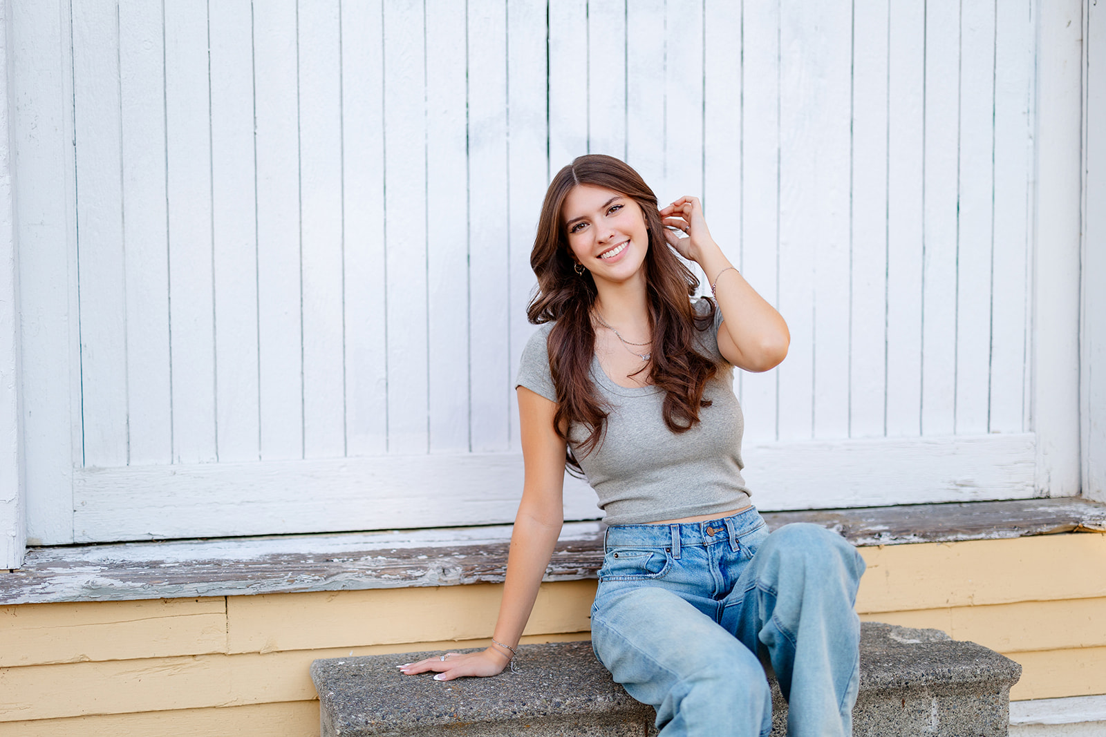 A Liberty High School Washington senior sits on a cement park bench pulling her brown hair back