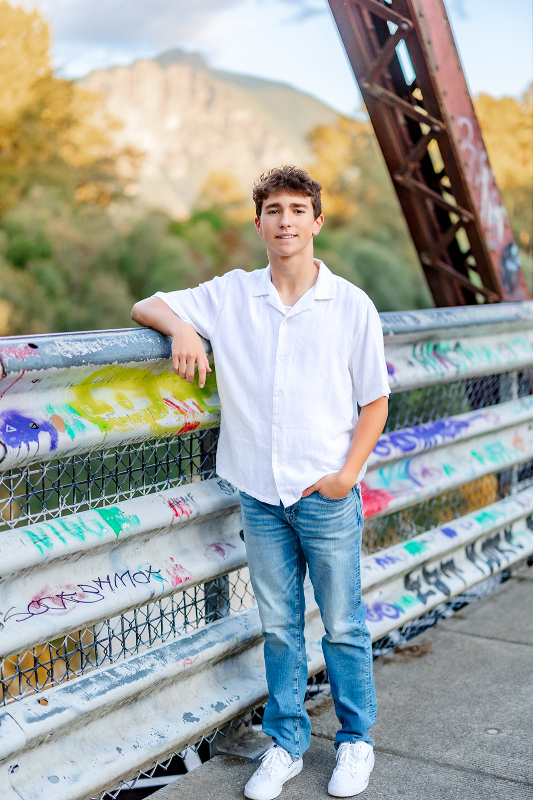 A high school senior leans on a graffitied bridge railing after succeeding with SAT Prep Issaquah