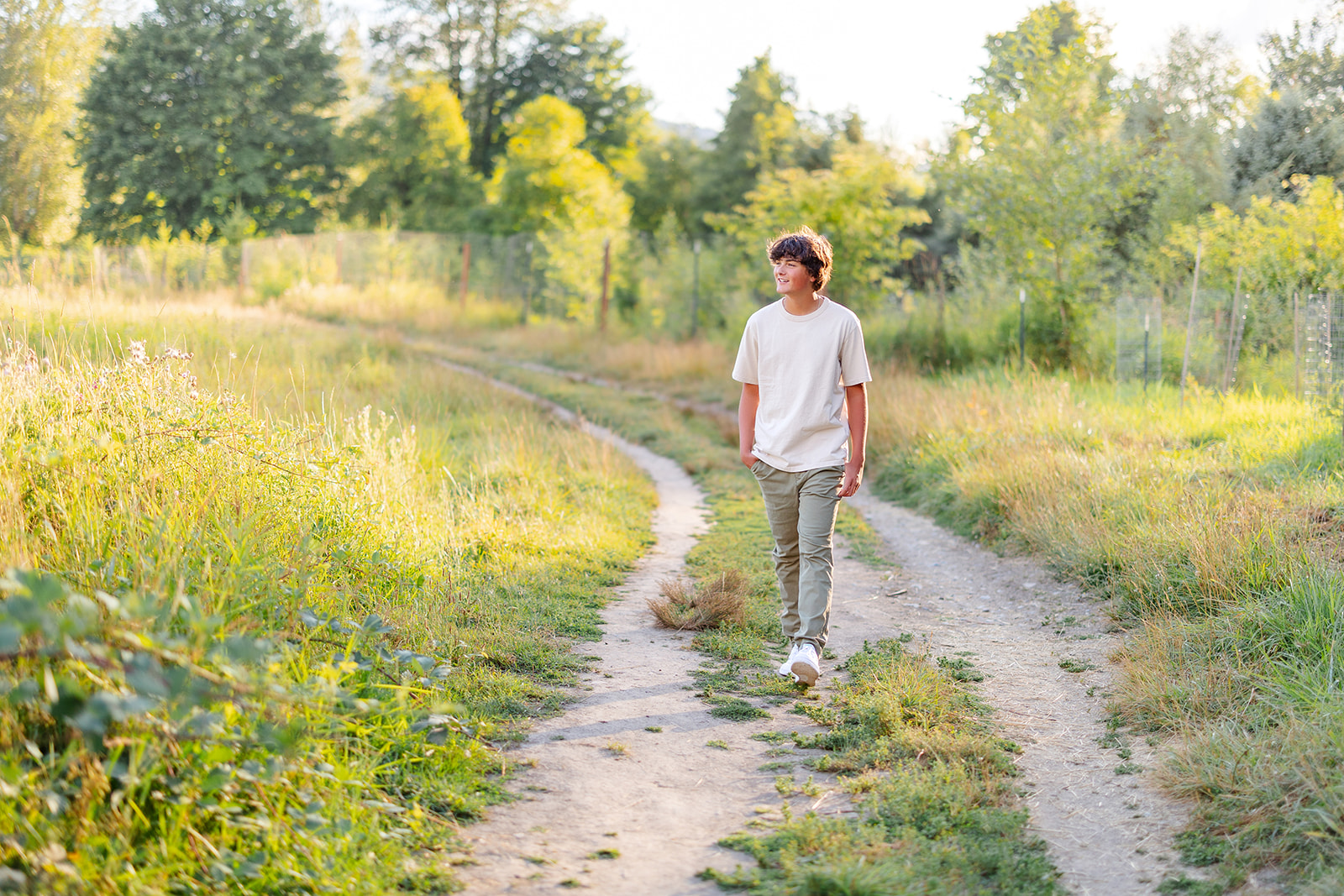 A high school senior boy hikes a trail at sunset in a white shirt and green pants after some SAT Prep in Kirkland