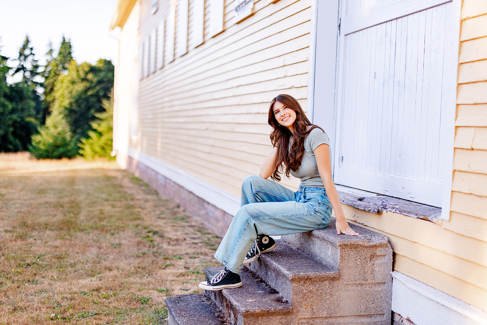 A teenage girl sits on concrete steps in a grey top and jeans