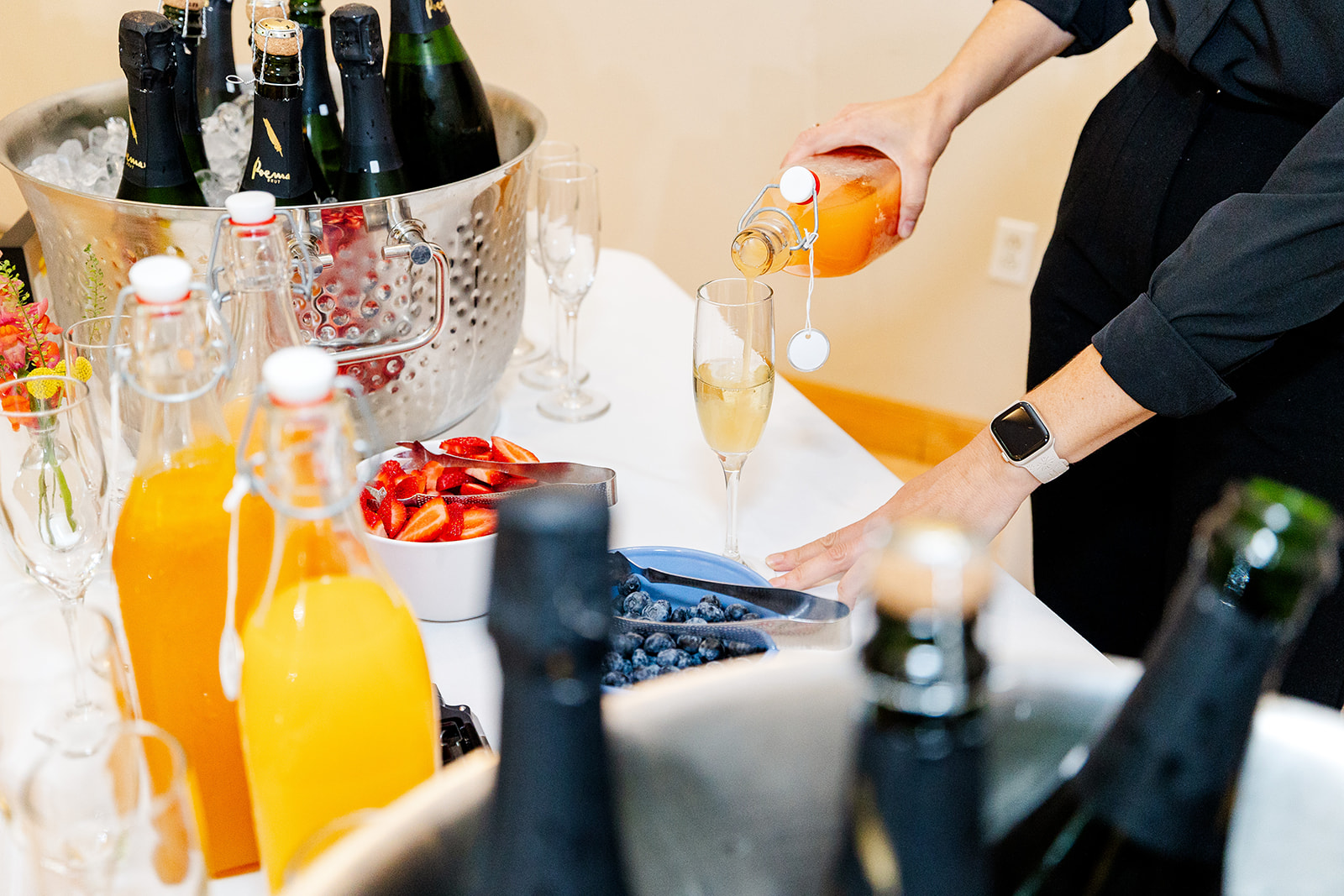 A person in black pours a drink in a champagne glass while catering in Mercer Island