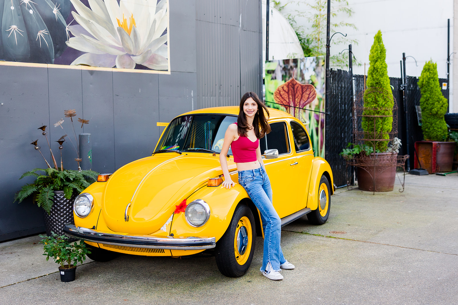 A high school senior leans on a yellow VW Beatle in a patio after finding Catering in Sammamish