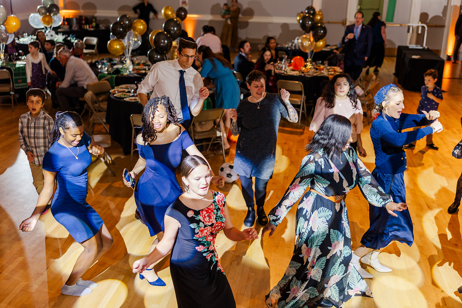 A group of woman dance on the wood floor during a CG Entertainment Mitzvah reception in blue dresses
