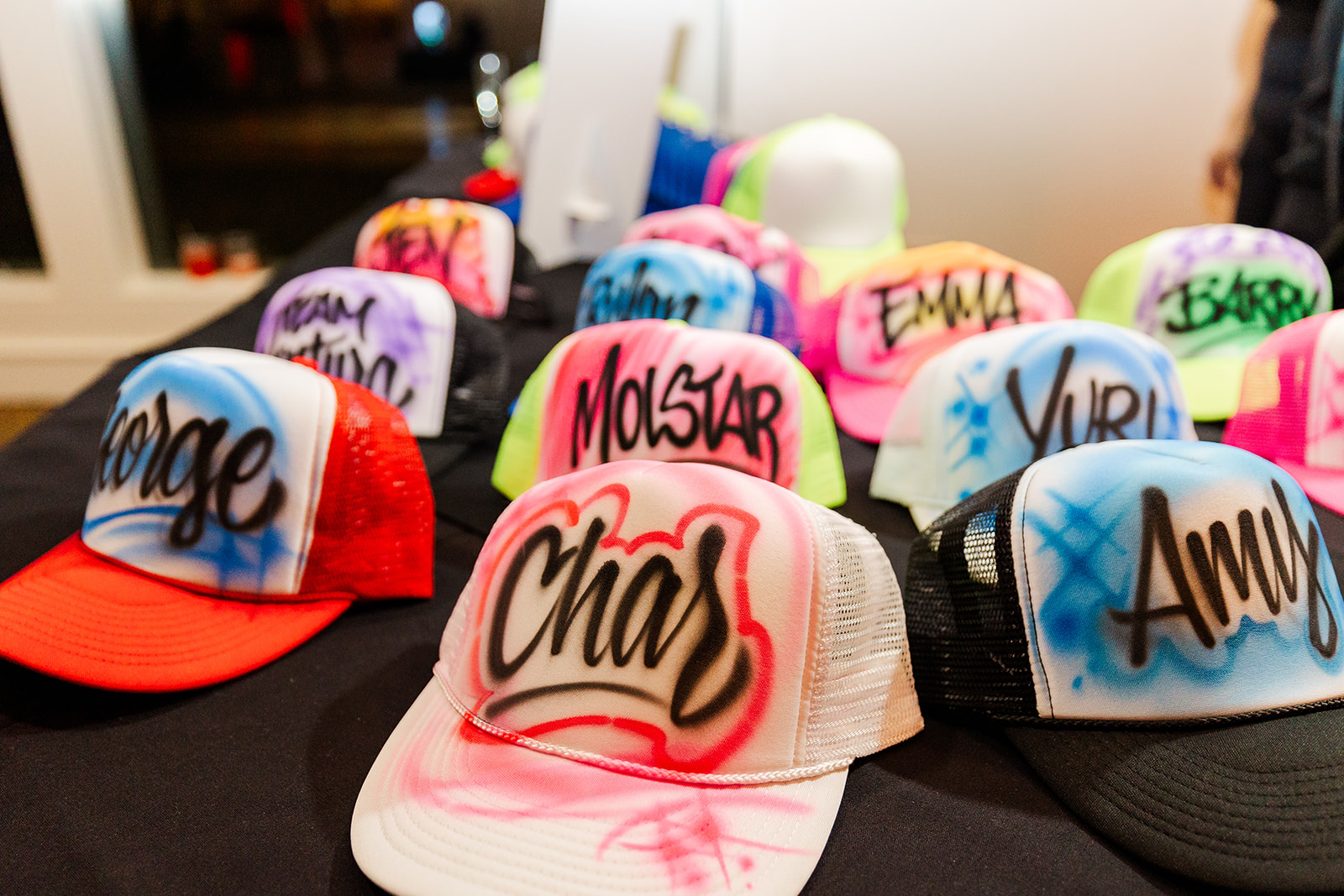 Details of custom hats on a table at a mitzvah being operated by DJs in Bellevue
