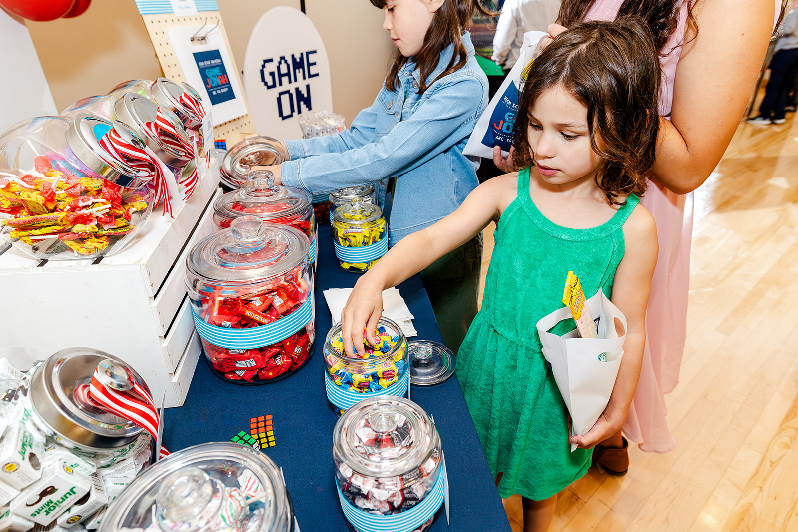 a young girl in a green dress chooses some candy from a candy table thanks to event planners in Kirkland, WA