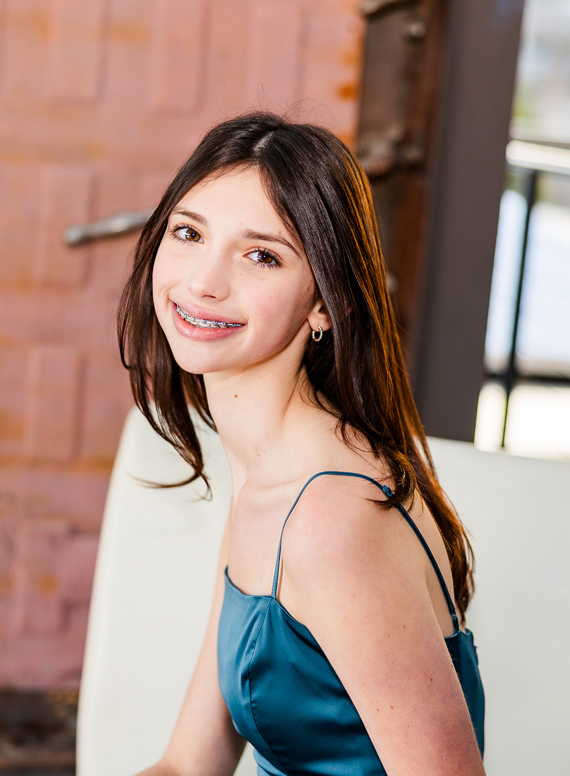 A happy teenage girl in a blue dress sits and smiles while exploring an Issaquah event space