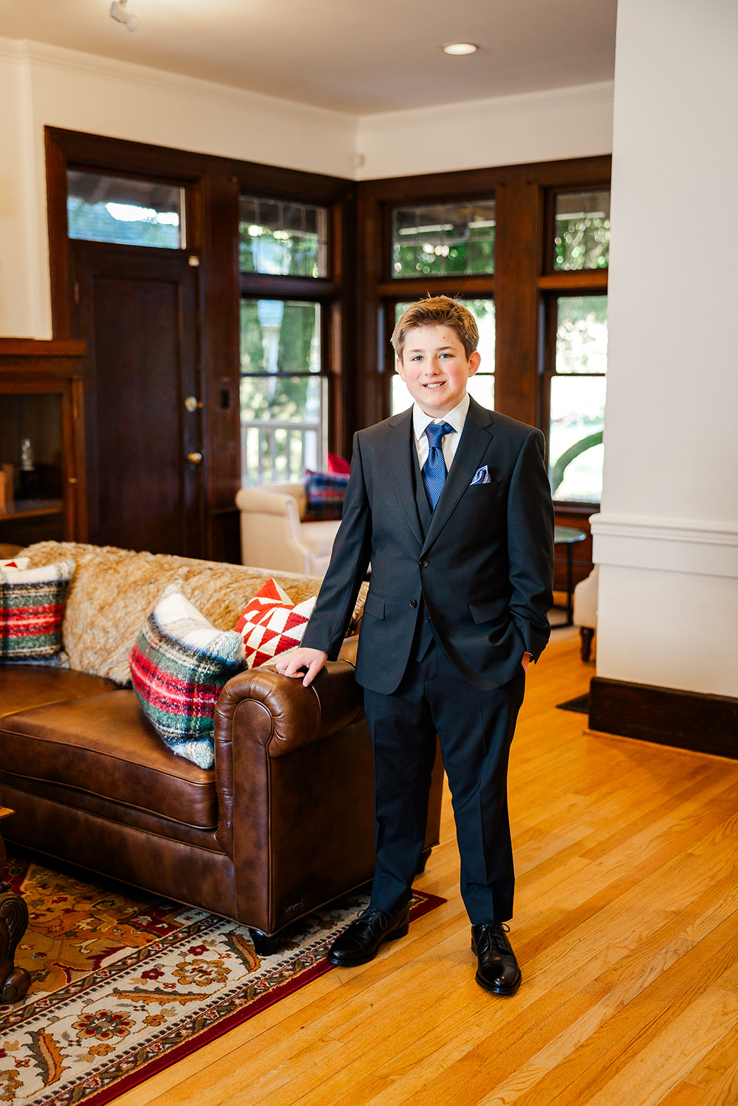 A young boy in a suit leans on a leather couch after finding perfect Issaquah party rentals