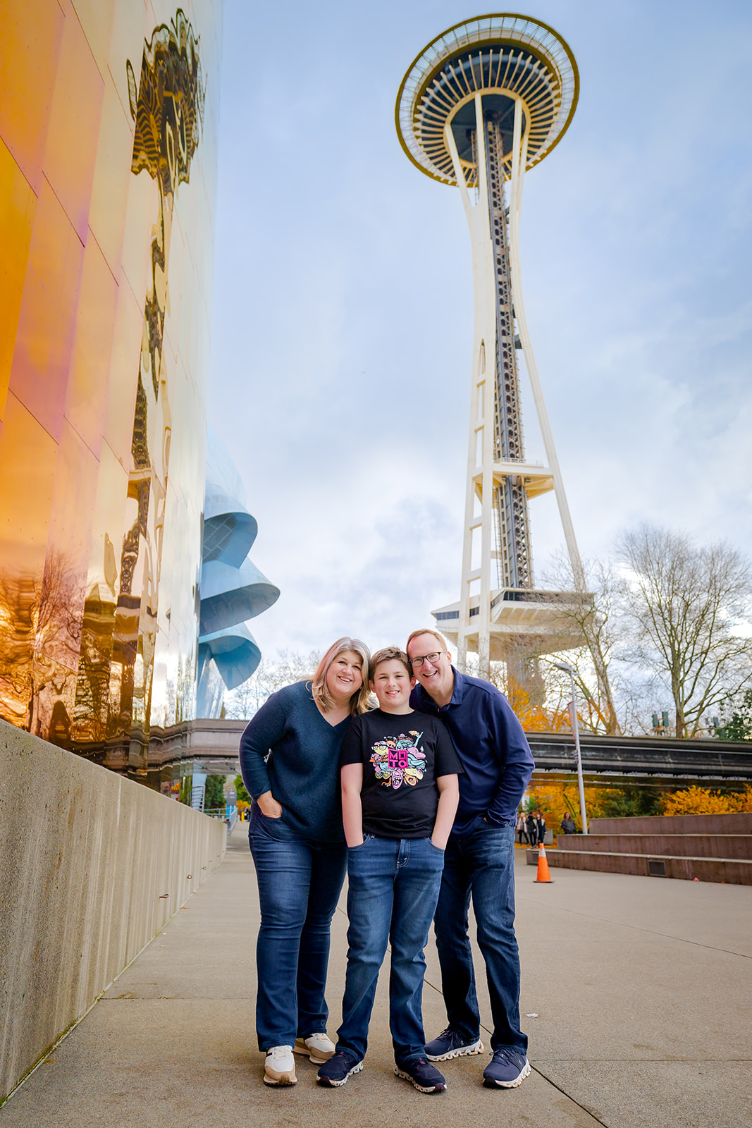Happy mom and dad smile with their teen son under the space needle