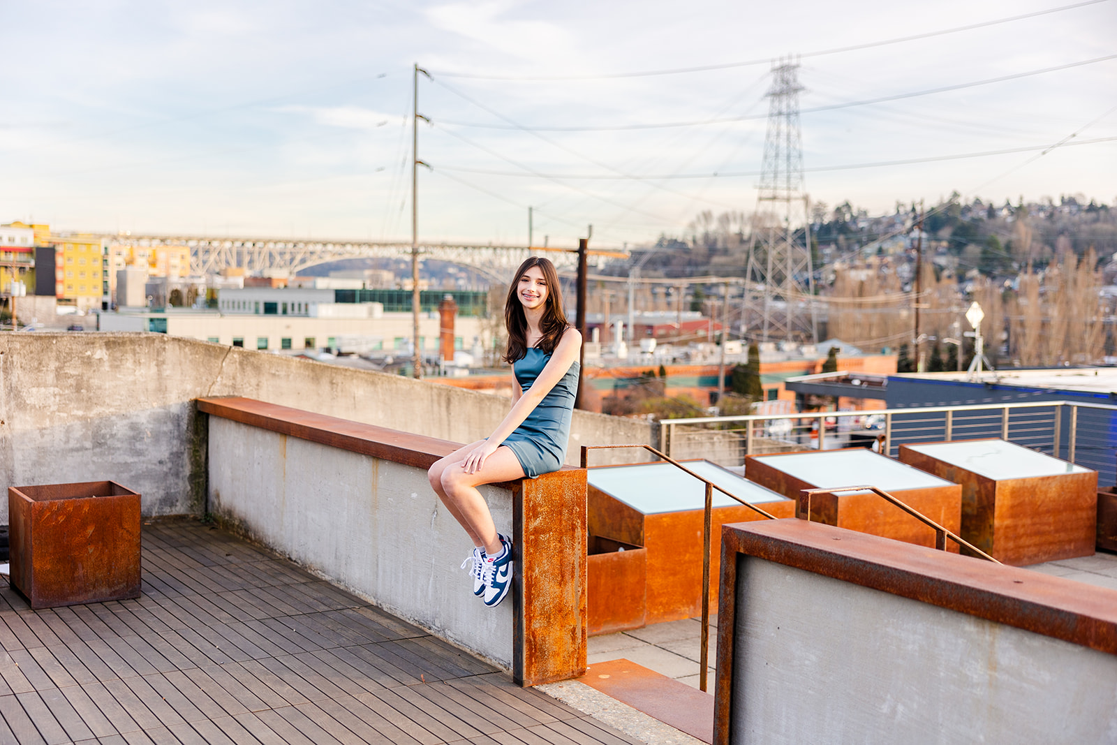 A teenage girl in a blue dress sits on a small rooftop wall at one of the Kirkland Event Spaces