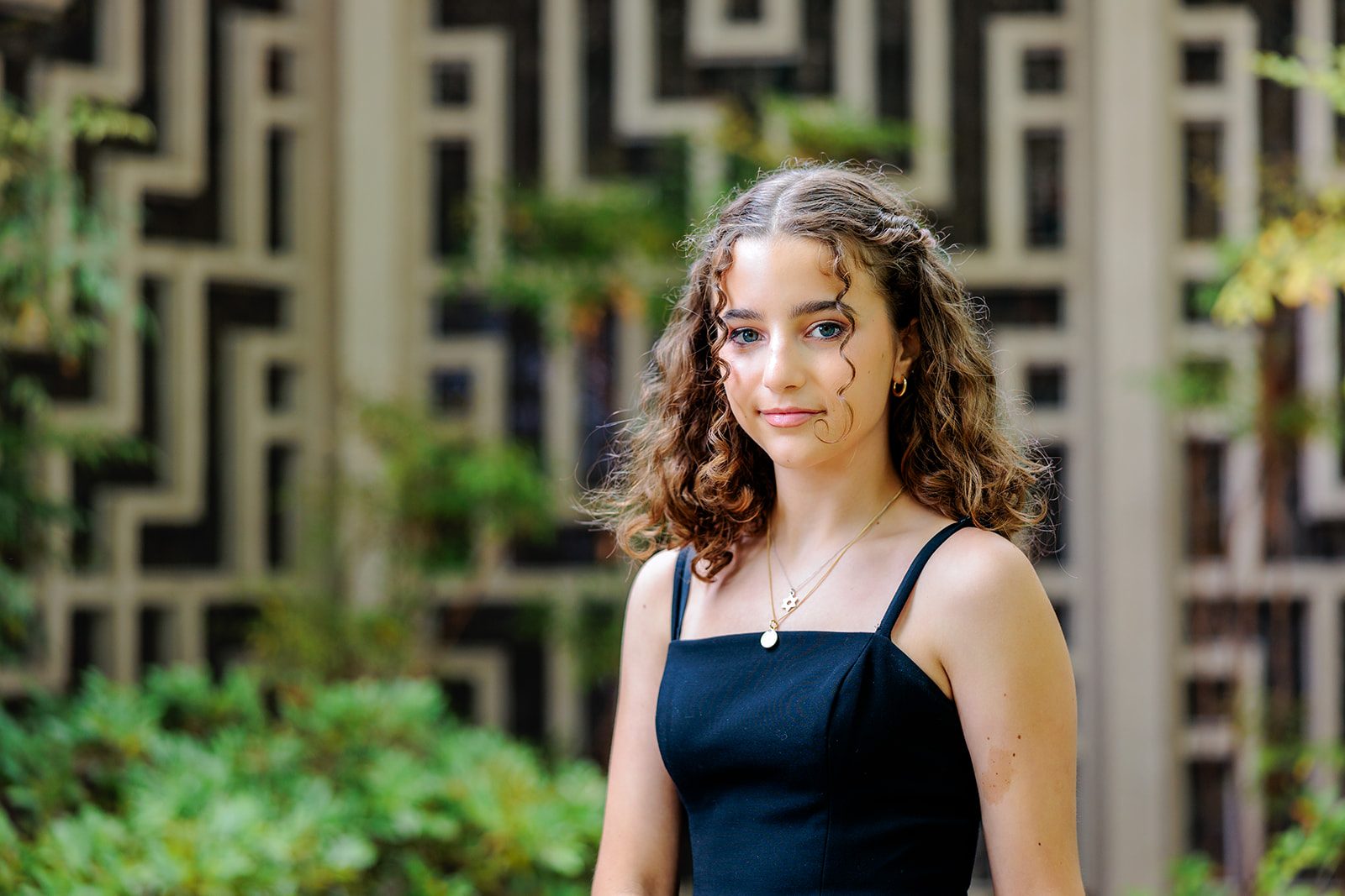 A teen girl in a black dress walks in a garden after her Bat Mitzvah before heading to large event venues in Seattle