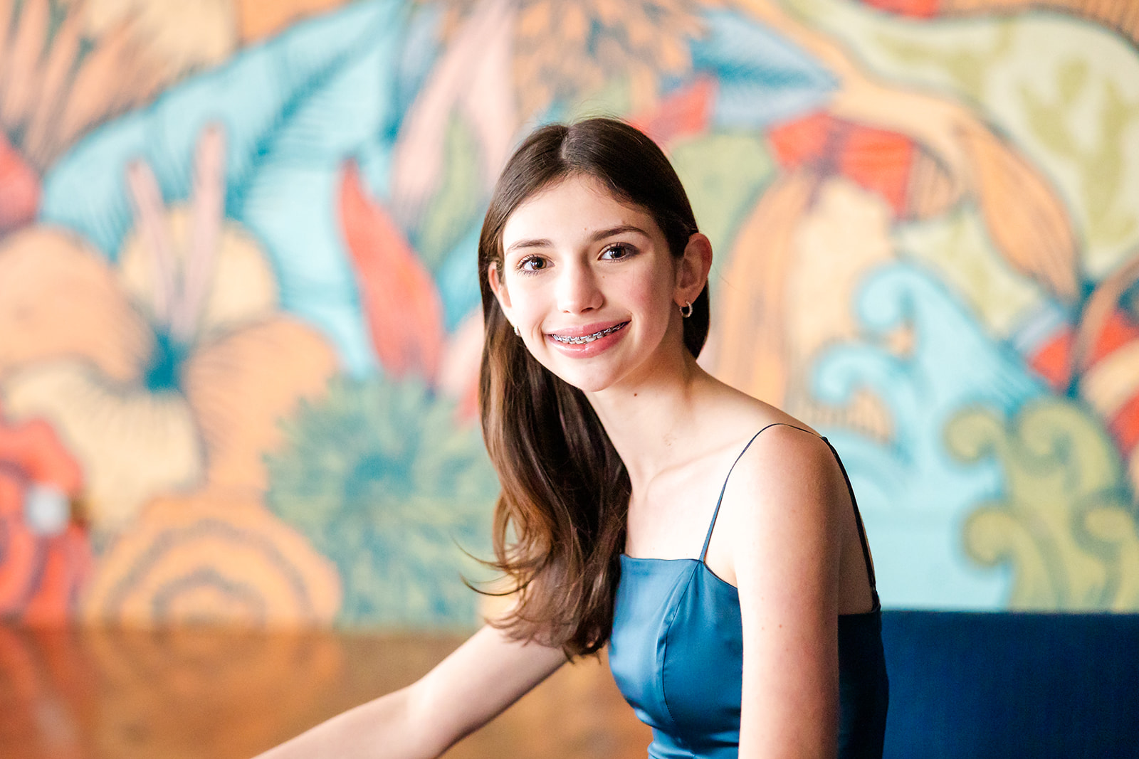 A teenage girl in a blue dress sits while smiling after finding private schools in Sammamish