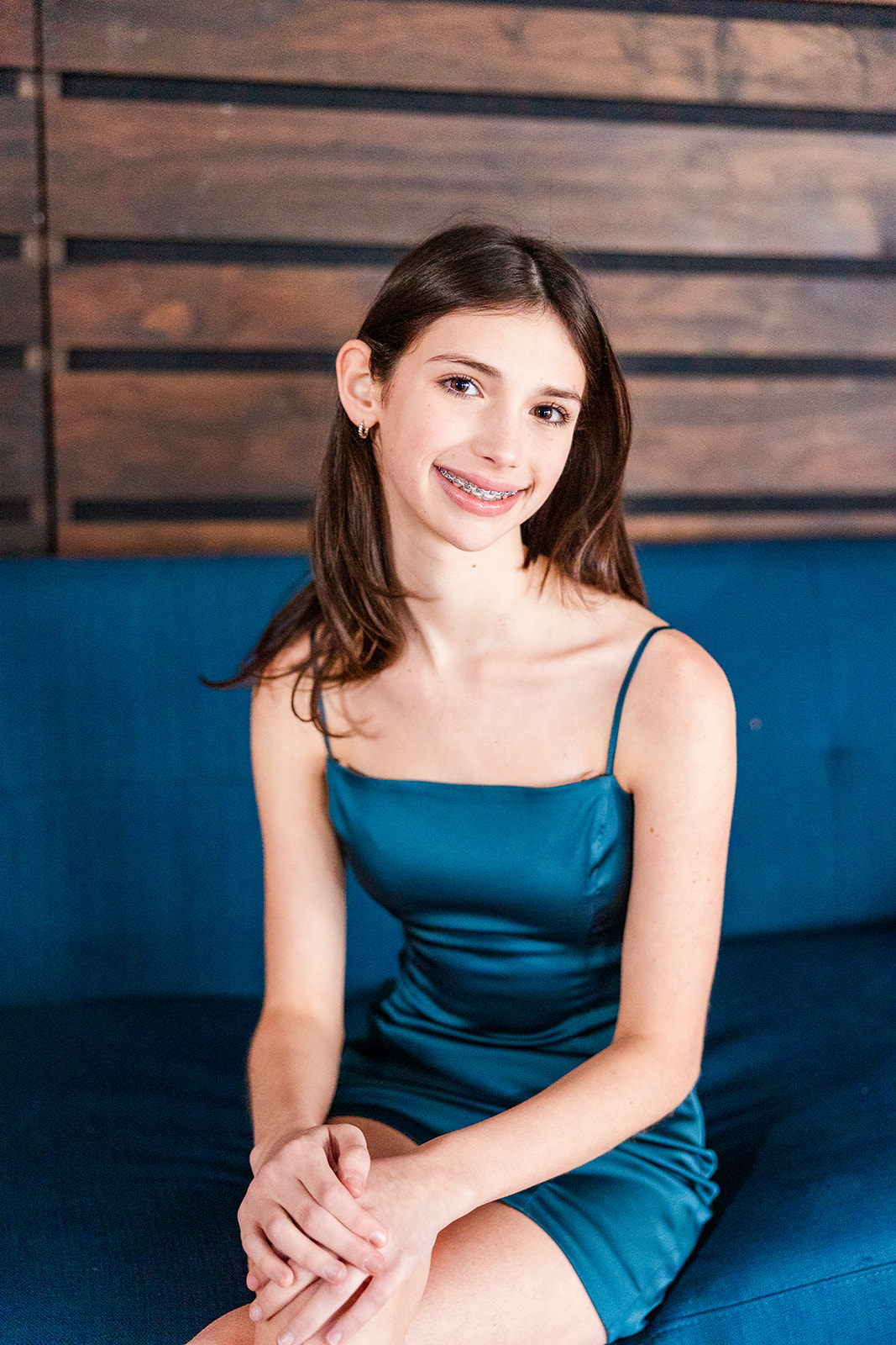 A high school senior in a blue dress sits on a patio couch after attending private schools in Sammamish