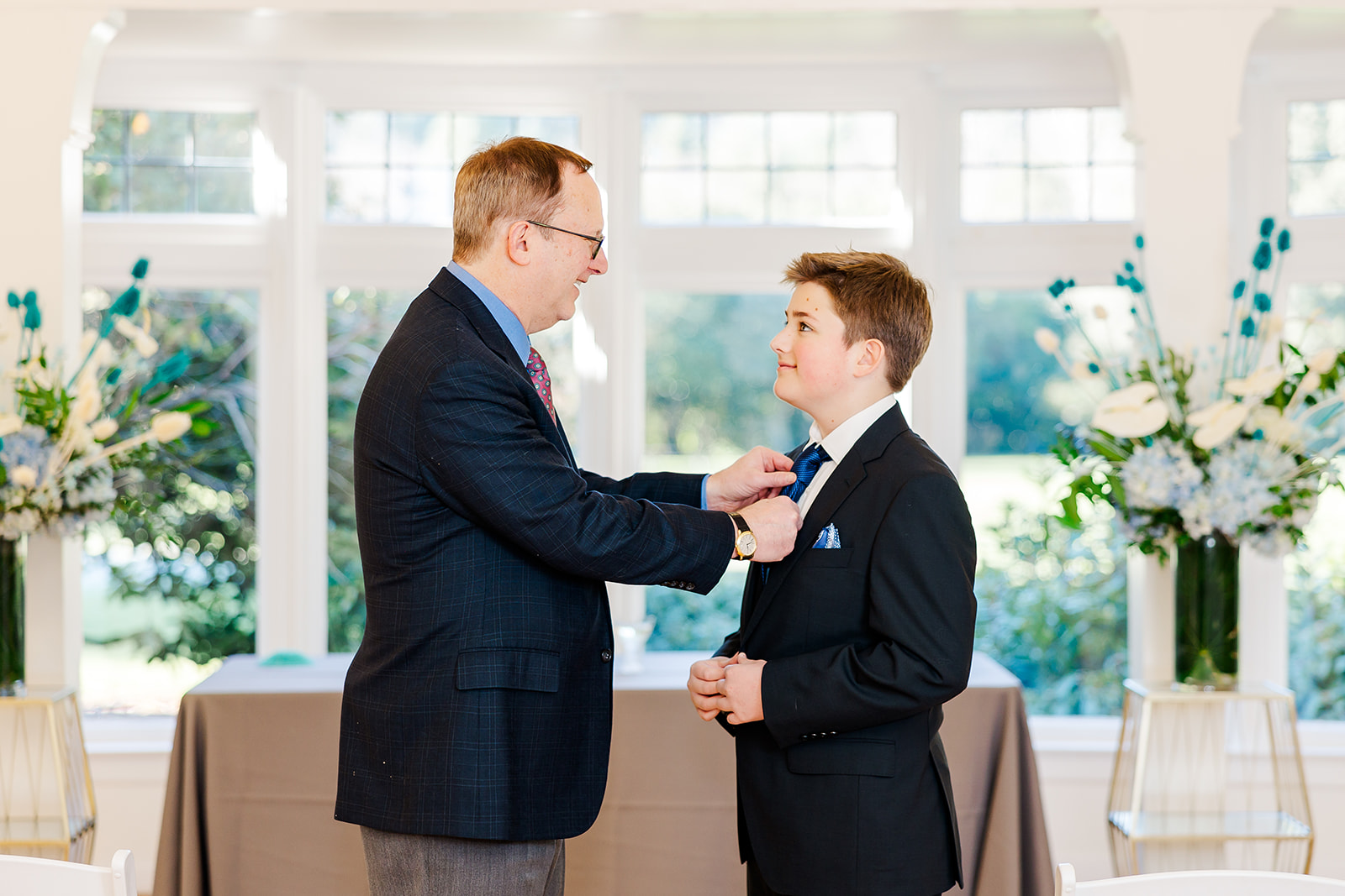 A proud dad in a suit helps adjust his sons tie for his Mitzvah after finding a great bakery on Mercer Island