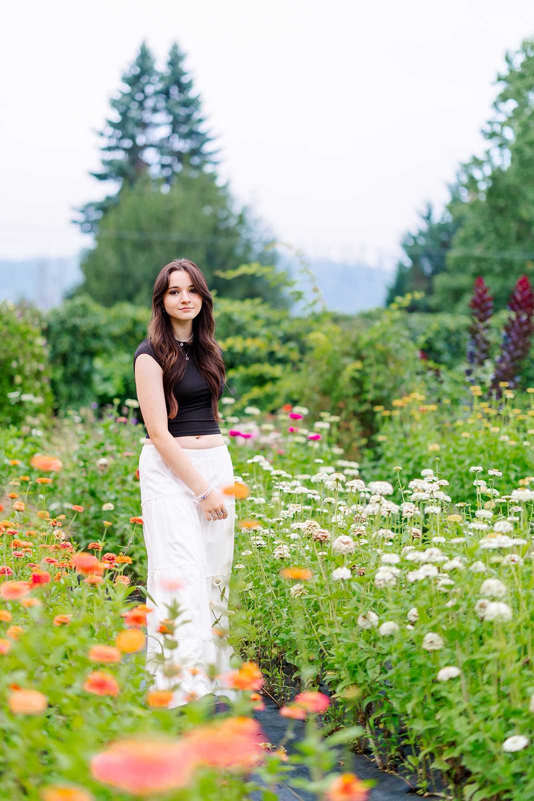 A CTE Dual Credit student explores a colorful garden in a black top and white pants