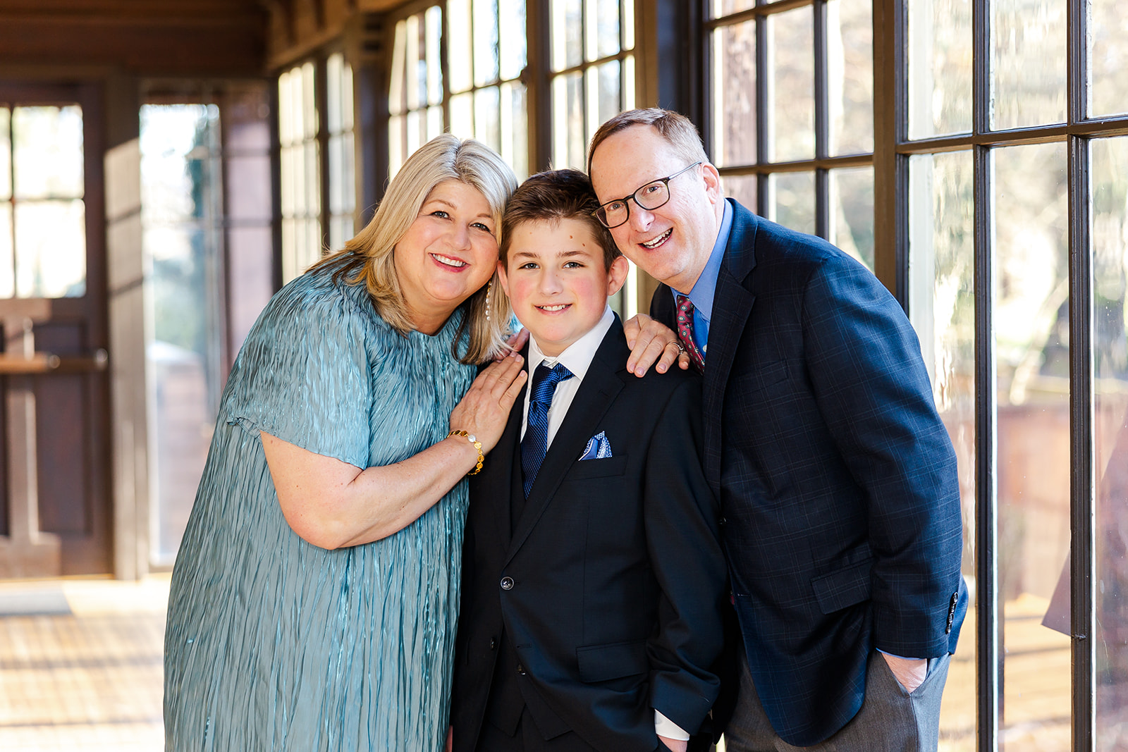 Happy mom and dad smile with their teen son for his bar mitzvah