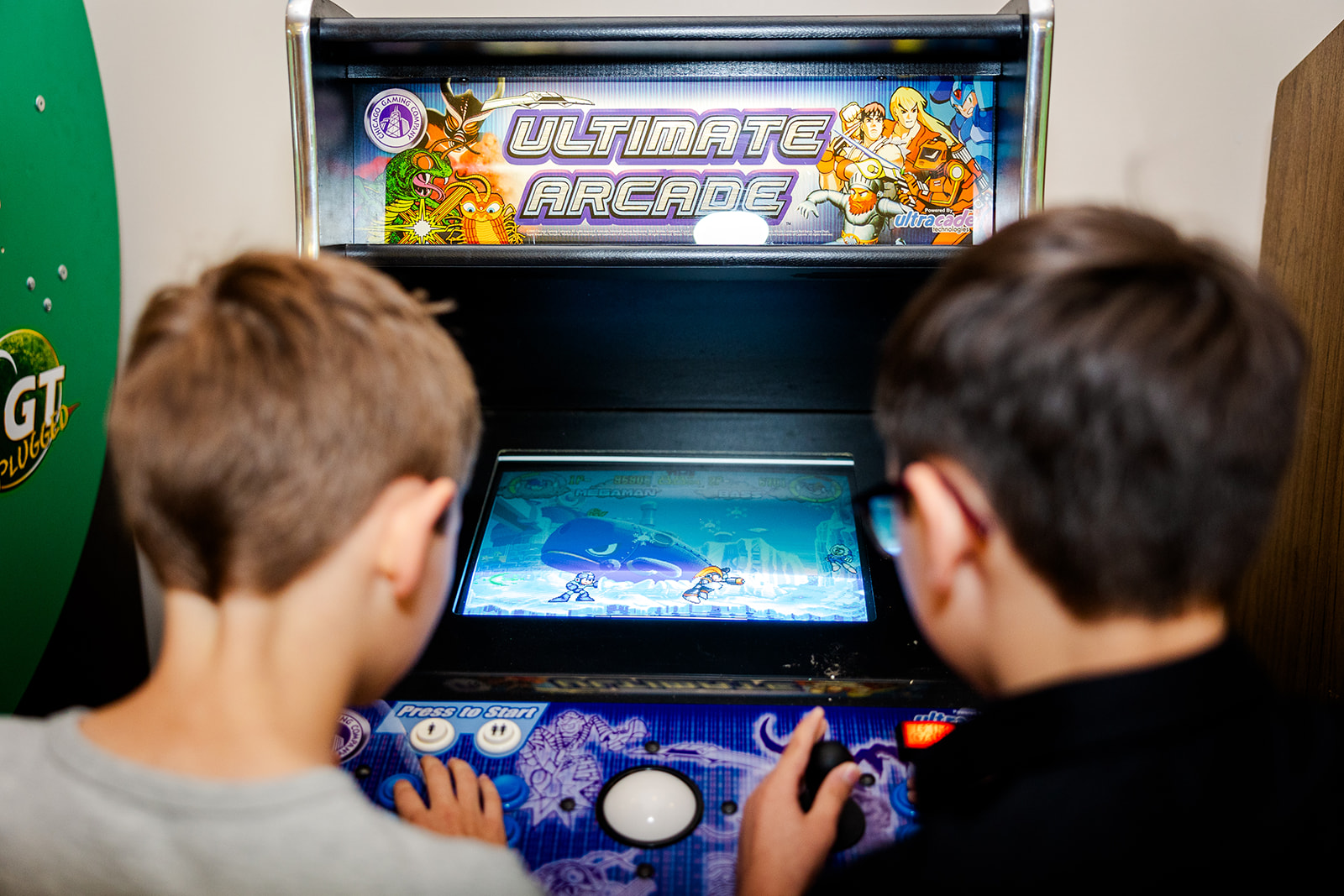 Two boys play an arcade game together at a bar mitzvah before heading to kid-friendly hotels in Seattle