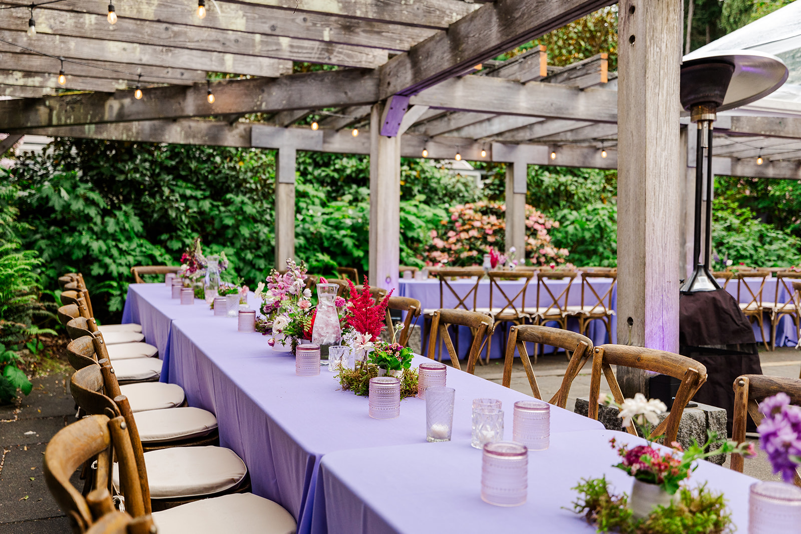 Details of a reception table with purple linen and florals under a pergola done by Seattle event decor